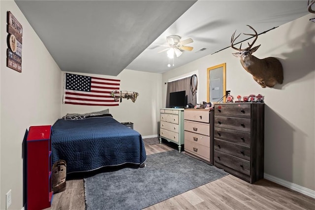 bedroom with baseboards, ceiling fan, wood finished floors, and visible vents