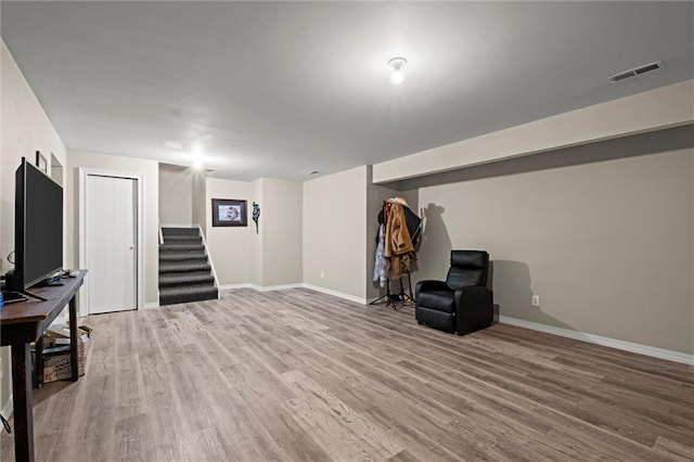finished below grade area with stairs, baseboards, visible vents, and light wood-style floors