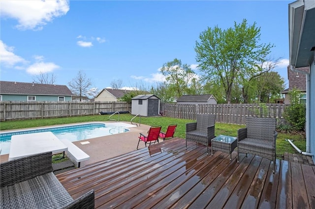 view of pool featuring a storage shed, a wooden deck, a fenced backyard, a lawn, and an outdoor structure