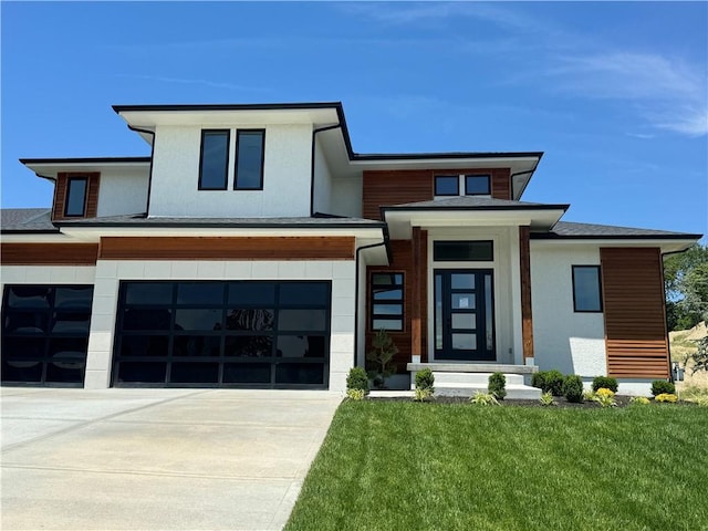 prairie-style home with a front lawn, concrete driveway, and an attached garage