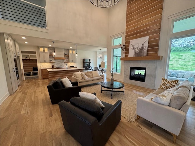 living area with light wood-style floors, a multi sided fireplace, a high ceiling, and plenty of natural light