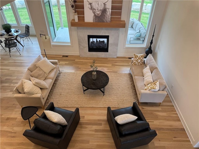 living room featuring a fireplace, visible vents, wood finished floors, and baseboards