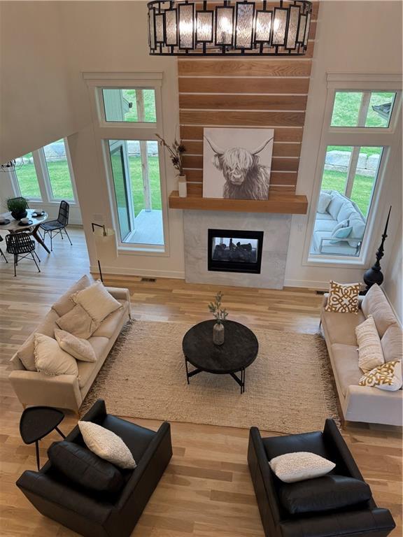 living room with a fireplace, wood finished floors, baseboards, and a high ceiling