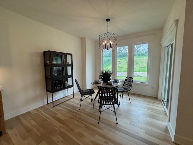 dining space featuring baseboards, a notable chandelier, and light wood-style flooring