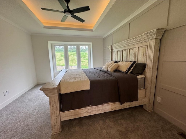 carpeted bedroom featuring ceiling fan and a tray ceiling