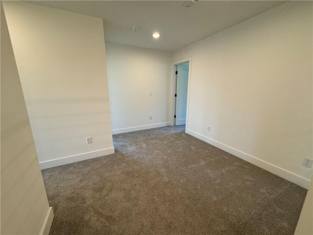 empty room featuring baseboards, dark colored carpet, and recessed lighting