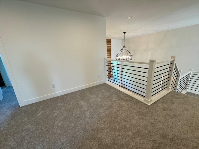 carpeted spare room featuring a chandelier and baseboards