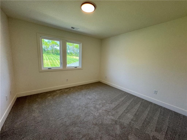 unfurnished room featuring visible vents, dark colored carpet, and baseboards