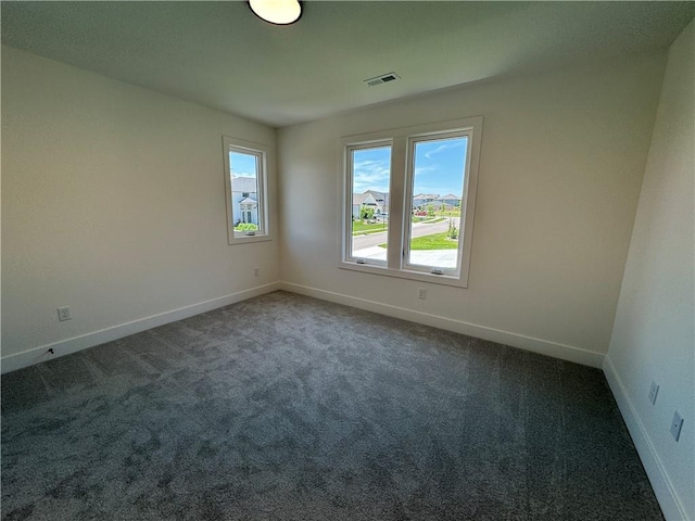 empty room with baseboards, visible vents, and dark carpet