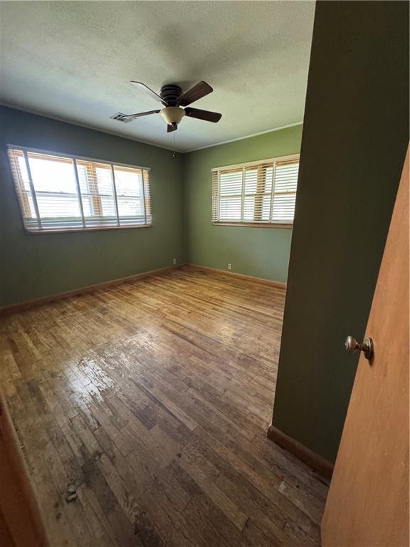 915 W 4th St, Chanute, KS 66720 - empty room with hardwood / wood-style flooring, ceiling fan, and a textured ceiling