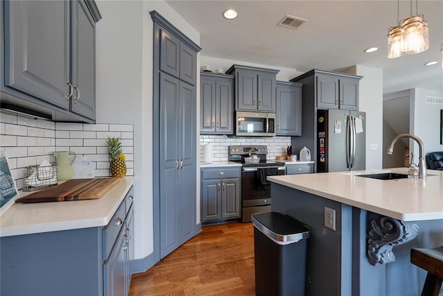 1008 SW Whippoorwill Ln, Oak Grove, MO 64075 - kitchen with stainless steel appliances, gray cabinetry, light countertops, wood finished floors, and recessed lighting