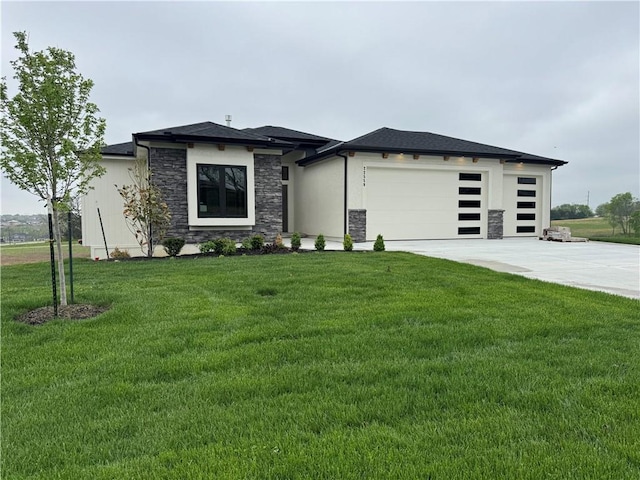 prairie-style home featuring concrete driveway, a front yard, an attached garage, and stone siding
