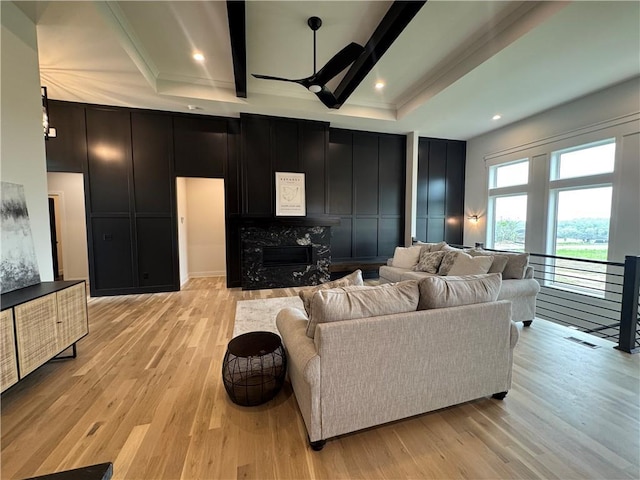 living room featuring a ceiling fan, a premium fireplace, a decorative wall, and light wood-type flooring