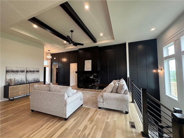 living room featuring visible vents, a wealth of natural light, light wood-style floors, and a decorative wall