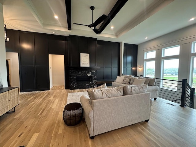 living room with ornamental molding, a premium fireplace, light wood-style flooring, and a decorative wall