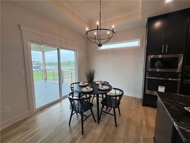dining room featuring a chandelier, baseboards, light wood-style floors, and a tray ceiling