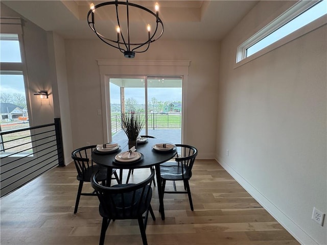 dining space featuring a notable chandelier, baseboards, and light wood-type flooring