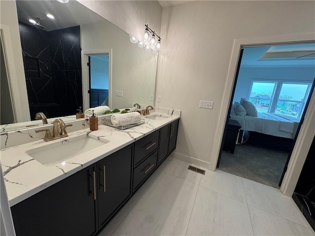 bathroom featuring double vanity, ensuite bathroom, baseboards, and a sink