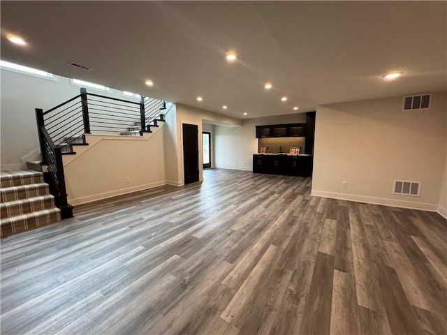 unfurnished living room with dark wood finished floors, visible vents, and stairs