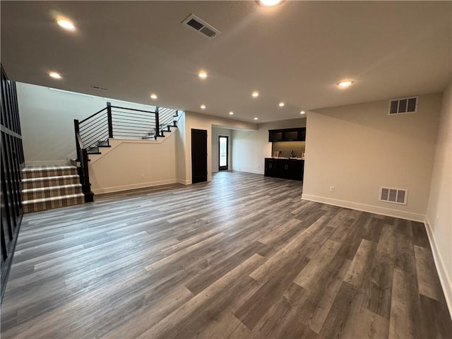 unfurnished living room featuring baseboards, visible vents, and stairs