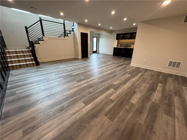 unfurnished living room with stairway, visible vents, baseboards, dark wood-style flooring, and recessed lighting