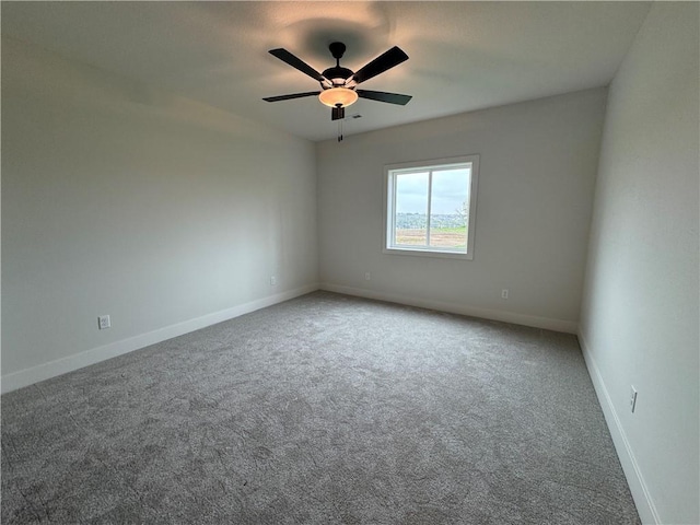 carpeted spare room featuring a ceiling fan and baseboards