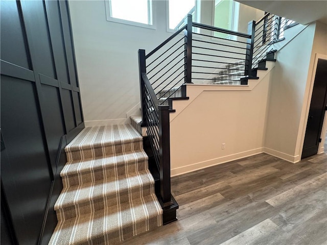 staircase featuring wood finished floors and baseboards