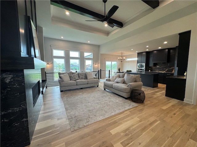 living area featuring recessed lighting, a fireplace, light wood-type flooring, crown molding, and ceiling fan with notable chandelier