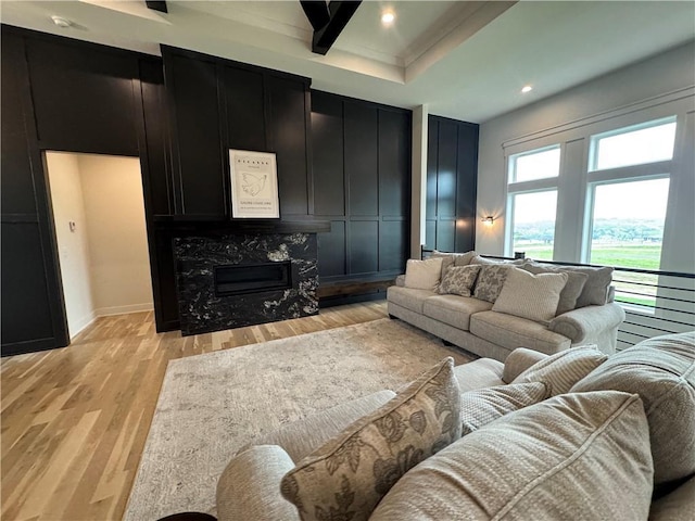 living room with baseboards, recessed lighting, a high end fireplace, and light wood-style flooring