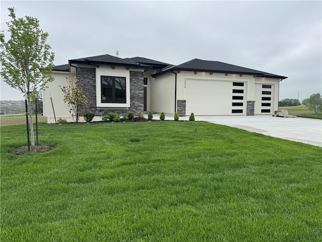 prairie-style house with a front yard, concrete driveway, stone siding, and a garage