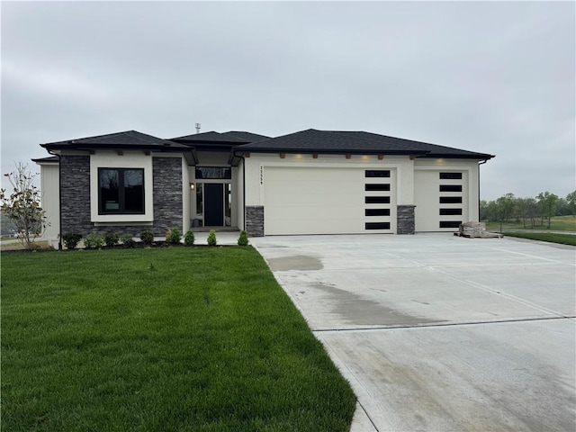 prairie-style house with a garage, concrete driveway, a front lawn, and stone siding