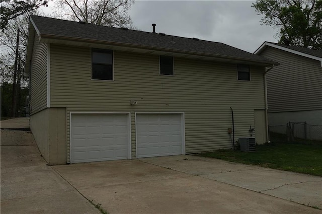 view of home's exterior featuring concrete driveway, a garage, central AC, and fence