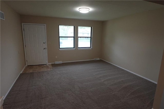 carpeted spare room featuring baseboards and visible vents