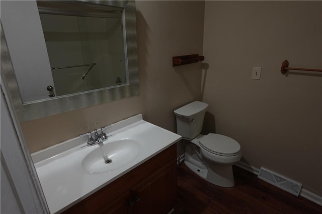 bathroom featuring wood finished floors, toilet, vanity, baseboards, and visible vents
