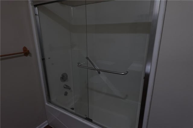bathroom with combined bath / shower with glass door and baseboards