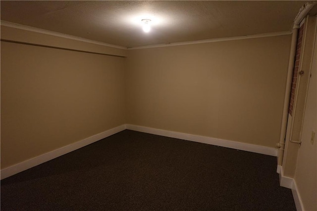 empty room with ornamental molding, dark colored carpet, and baseboards