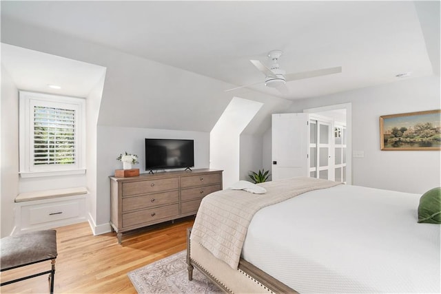 bedroom featuring baseboards, a ceiling fan, light wood-style flooring, and lofted ceiling