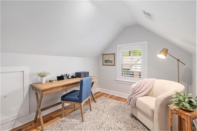 home office featuring baseboards, visible vents, lofted ceiling, and light wood-style floors