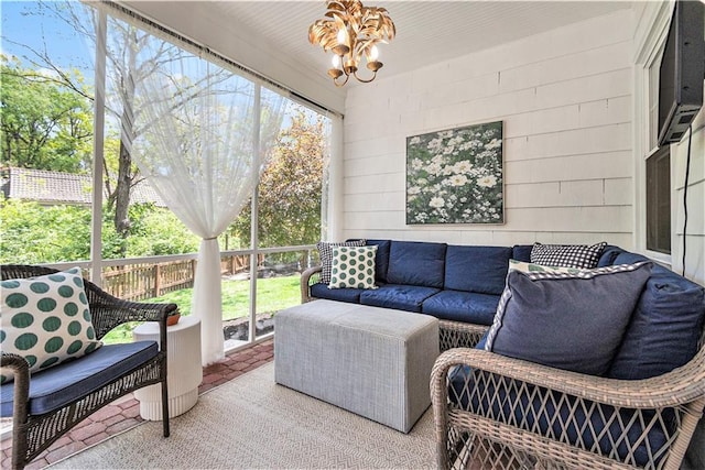sunroom featuring ceiling fan with notable chandelier and outdoor lounge area