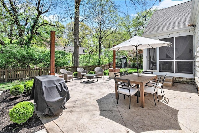 view of patio / terrace with a sunroom, a fenced backyard, a grill, and outdoor dining space
