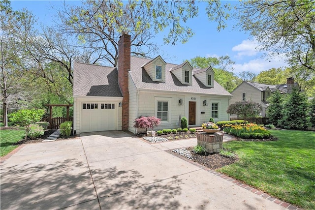 new england style home featuring a front lawn, roof with shingles, a chimney, an attached garage, and driveway