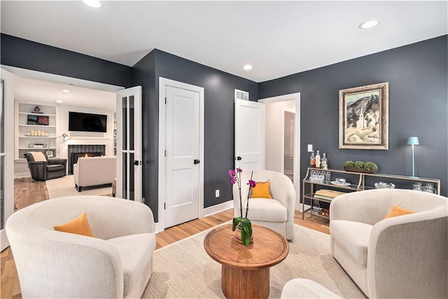 living area featuring recessed lighting, baseboards, a tiled fireplace, and wood finished floors