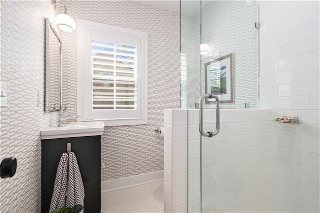 bathroom featuring vanity, wallpapered walls, and a shower stall