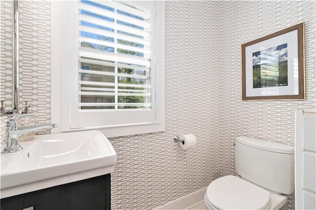 half bath with a sink, toilet, and wallpapered walls