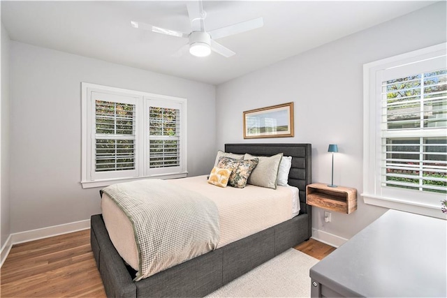 bedroom featuring baseboards, multiple windows, and wood finished floors