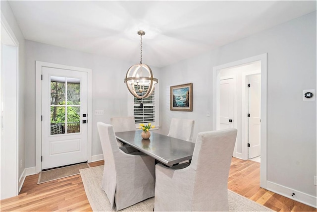 dining space with light wood-style floors, baseboards, and a chandelier