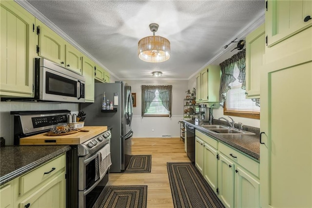2931 N Washington St, Chillicothe, MO 64601 - kitchen with green cabinetry, dark countertops, a sink, light wood-style flooring, and appliances with stainless steel finishes