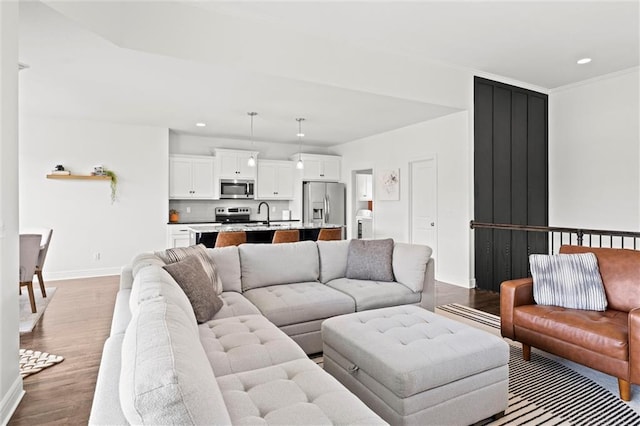 living area featuring baseboards, recessed lighting, dark wood-style flooring, and crown molding