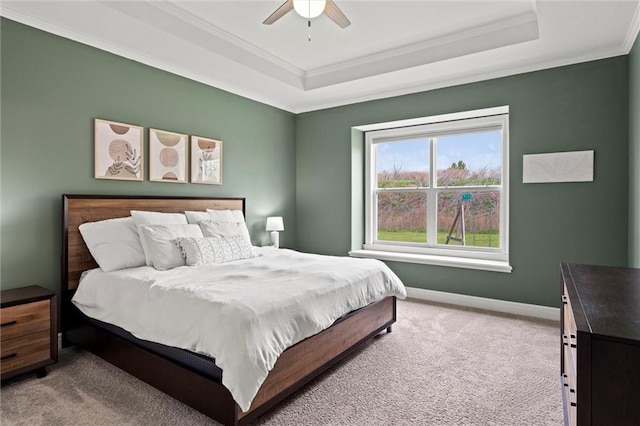 carpeted bedroom with baseboards, ornamental molding, ceiling fan, and a raised ceiling