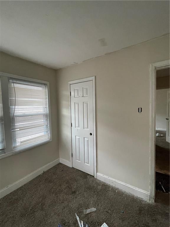 2000 S Overton Ave, Independence, MO 64052 - unfurnished bedroom with baseboards and dark carpet